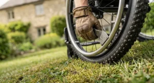 A modern manual wheelchair with large wheels folded flat and stored securely in the boot of a blue hatchback car.