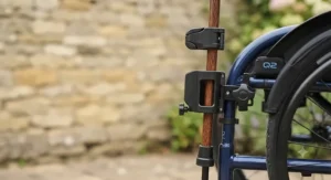 Side view showing the walking stick holder mechanism mounted on a wheelchair frame.