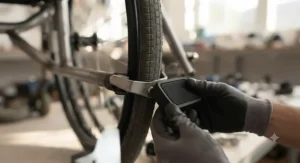 A close-up of a new rubber brake footpad being installed onto a wheelchair wheel lock mechanism.