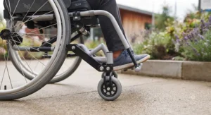 Close-up diagram of a wheelchair anti-tipper wheel attachment mounted on the rear frame of a mobility aid.