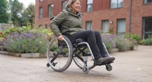 Manual wheelchair user safely navigating a dropped kerb on a British high street with anti-tippers fitted.