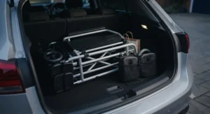 A foldable transit wheelchair with its removable footrests detached, packed neatly into a car boot for travel.