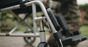 Close-up of a quick-release lever used to detach removable footrests on a standard transit wheelchair.