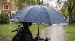 A durable hands-free wheelchair umbrella shielding a user effectively from heavy British rainfall.